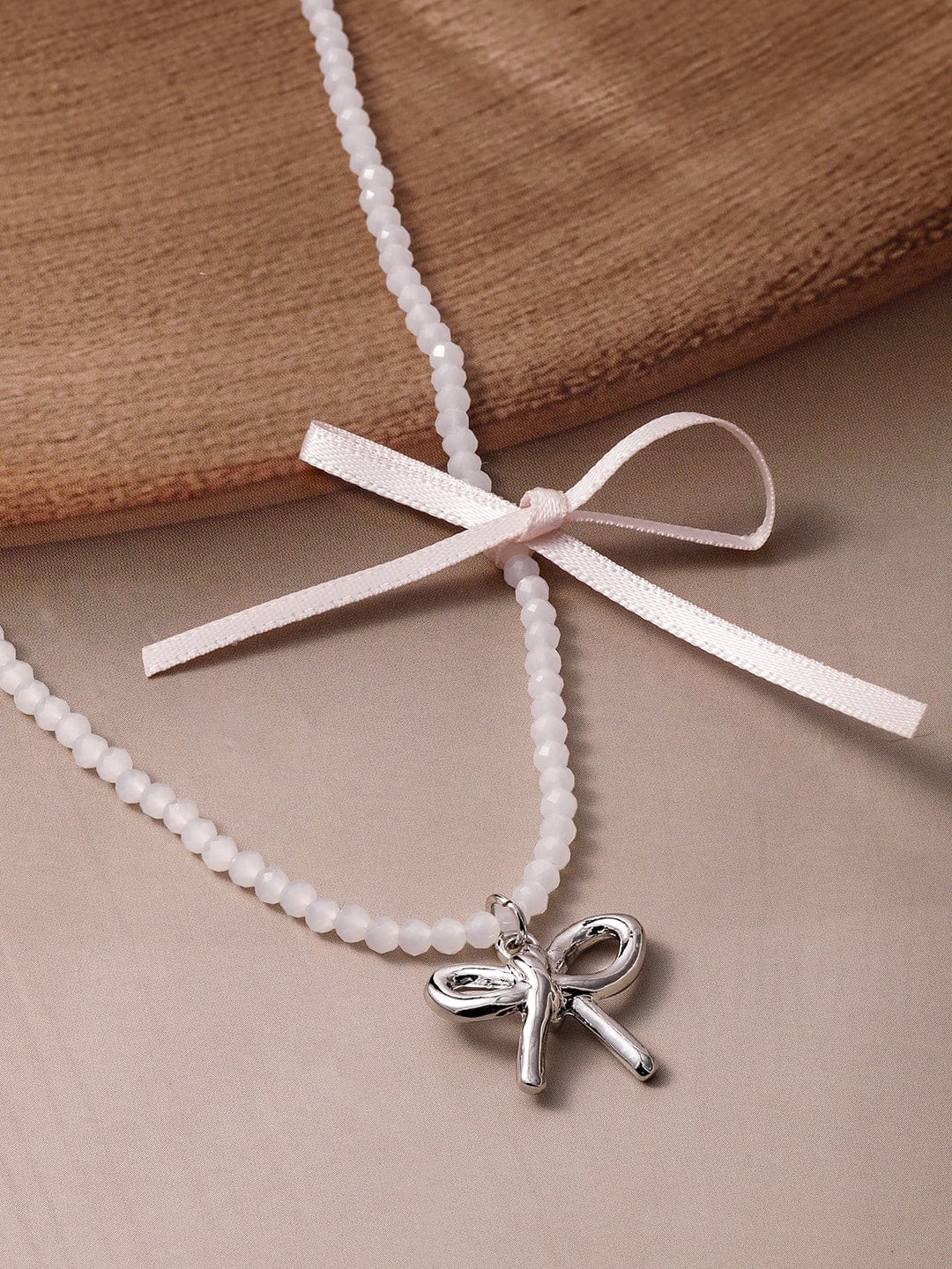 Silver Bow Pendant on Cream Colored Beaded Chain Necklace